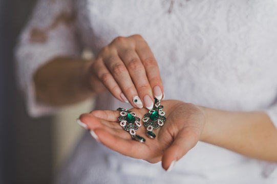 Earrings with green stones in the womens hands 8828.