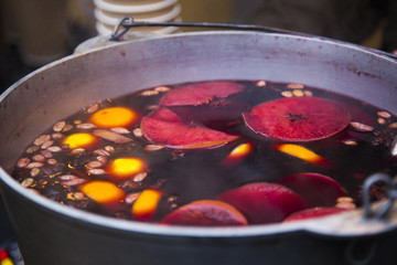 Pot of dark red hot mulled wine, glintwein with slice of orange and lemon