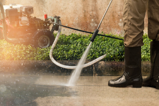 High pressure deep cleaning..Worker cleaning driveway with gasoline high pressure washer ,professional cleaning services.