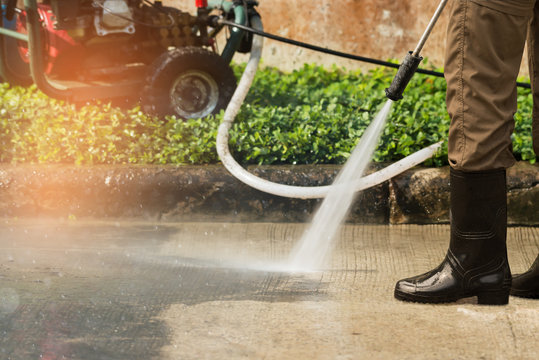 High pressure deep cleaning. .Worker cleaning driveway with gasoline high pressure washer ,professional cleaning services.