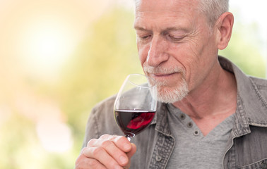 Mature man tasting red wine, light effect
