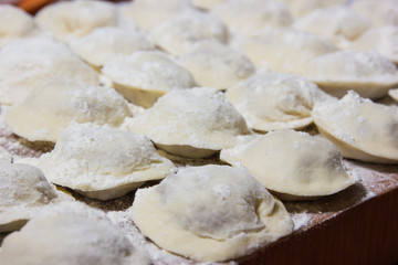 Fototapeta na wymiar dumplings in flour on the table. Raw dumplings with handmade meat close-up.