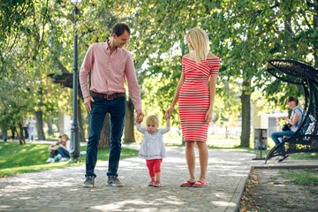 Family walking in the park. mom and daddy going hand in hand with a baby