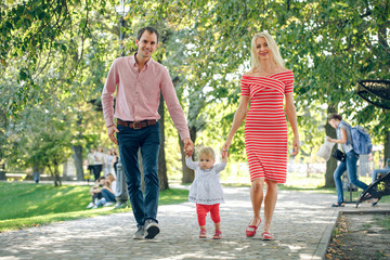 Family walking in the park. mom and daddy going hand in hand with a baby