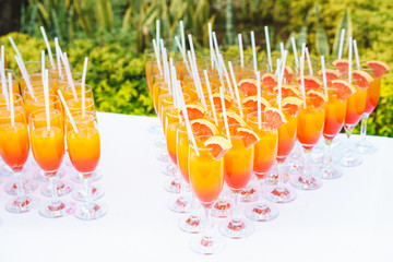 
Orange juice cocktail in a flute glasses and slice of fresh orange with draw on white table,Party outdoor.
