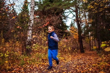 Little boy running in autumn forest