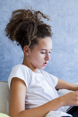 Curly hair girl using digital tablet on sofa