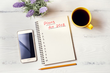 Red inscription "Plans for 2018"  in notebook on white desk
