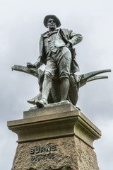 Obraz premium Sydney, Australia - March 23, 2017: Closeup of figure on top of pedestal, an all bronze statue of Robert Burns on side of Vernon building of Art Gallery of NSW. Against silver sky.
