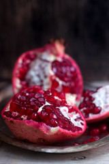 Cut a piece of ripe pomegranate on a wooden background.