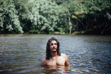 Young man, backpacker, inside the lake, at a tropical forest