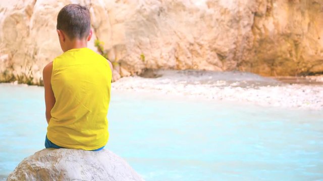 Back view of child sitting on stone