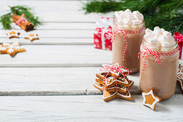 Christmas mood - chocolate in a bottle with marshmallows, fir branch, gift and gingerbread