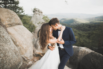 Gorgeous bride, groom kissing and hugging near the cliffs with stunning views
