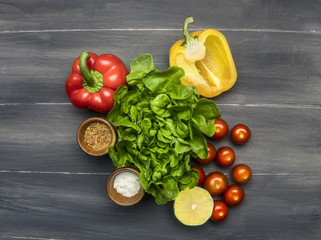concept of cooking vegetarian food, useful, vitamin-rich vegetables and fruits, salad, bell peppers, lime, cherry tomatoes,lime, lined on a wooden rustic background