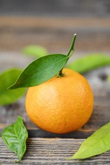 Fresh tasty tangerines with leaves on wooden table 