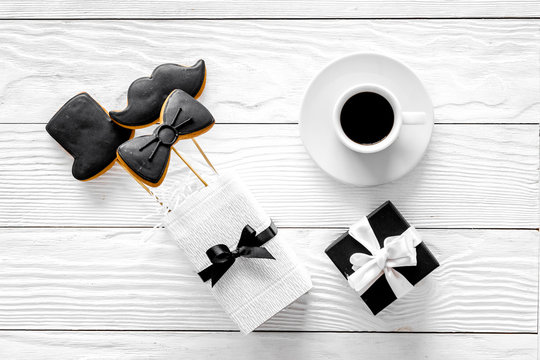 Birthday gift for men. Wrapped box, cookies in shape of black tie, mustache, hat. White wooden background top view