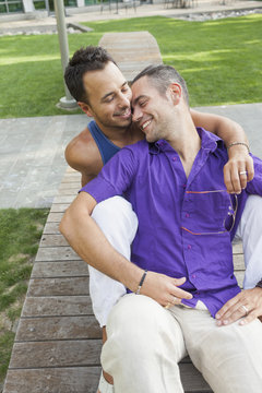 Romantic gay couple sitting on a park bench