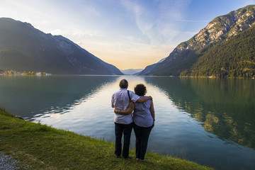 Fototapeta na wymiar Senior couple watching sunset at Lake Achen (Achensee), a lake north of Jenbach in Tyrol, Austria