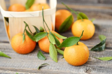 Fresh tasty tangerines with leaves on wooden table 