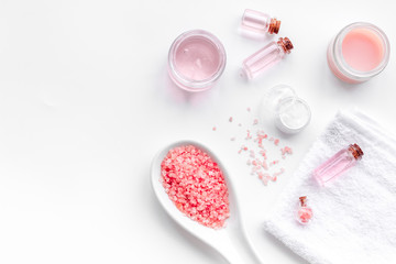 Spa products with rose oil. Cream, lotion and salt on white background top view copyspace