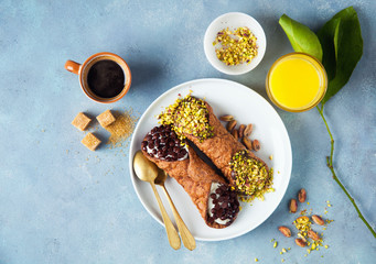 Cannoli with ricotta, chocolate and pistachios. Italian pastries of the Sicily . classic breakfast with orange juice and coffee - obrazy, fototapety, plakaty