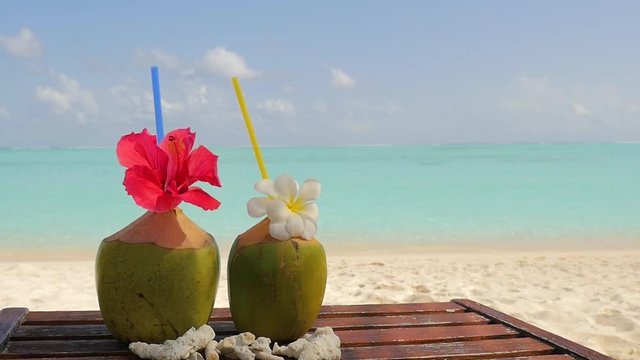 Tropical fresh coconut cocktail on white beach. Two coconut drinks on luxury tropical resort in Maldives island. Fresh green coconut cocktails on sandy Maldives beach with turquoise sea background.