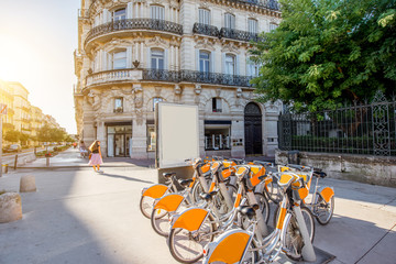 Street view with beautiful old buildings and bicycle parking on the Foch boulevard during the morning light in Montpellier city in France - obrazy, fototapety, plakaty