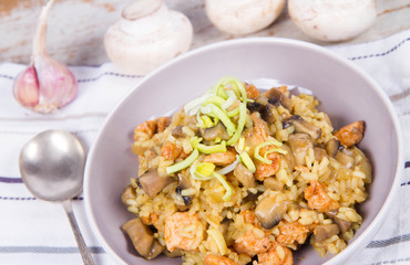 Risotto with mushrooms and chicken decorated with leek on a wooden background