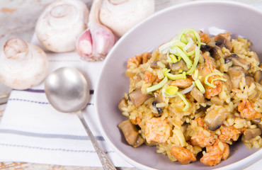 Risotto with mushrooms and chicken decorated with leek on a wooden background