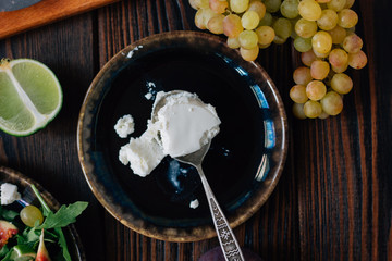 Ricotta cheese on black ceramic plate with grapes ready to eat.