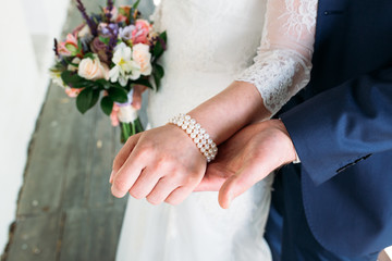 Detail of bride's bouquet and hands holding