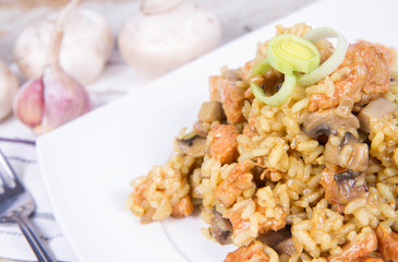 Risotto with mushrooms and chicken decorated with leek on a wooden background 