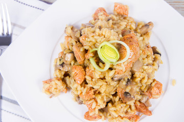 Risotto with mushrooms and chicken decorated with leek on a wooden background 