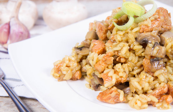 Risotto with mushrooms and chicken decorated with leek on a wooden background 