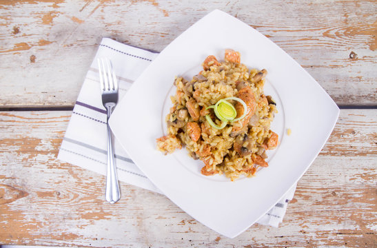 Risotto with mushrooms and chicken decorated with leek on a wooden background 