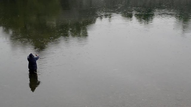 Man fishing in a river. Rainy day