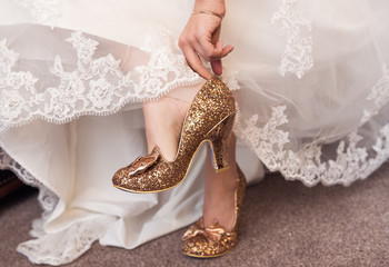 A bride putting on her wedding shoes in preparation for the wedding ceremony. Soft delicate white and cream colours. feet and shoes.