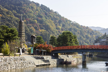 The Thirteen Story Stone Pagoda at Uji, Japan, next to a red wooden bridge