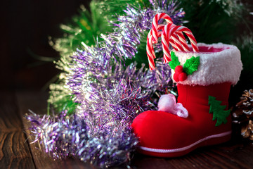 Christmas decoration - red boot with candy canes on dark wooden background.
