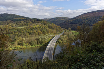 top view, cars on a breidge over the river and forest landscape in autumn colors