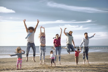jumping on beach. mixed race kids with diverse young parents on beach having fun together.