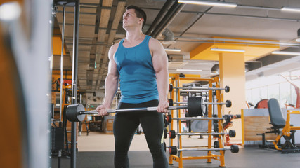 Fototapeta na wymiar Bodybuilding in the gym - muscular man training his biceps near mirror