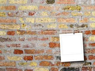 Blank square photo frame hanged by peg against weathered brick wall background
