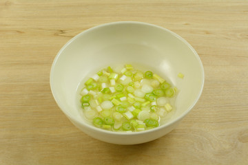 Chopped white ends of green onion scallion whites soaking white wine vinegar in white bowl