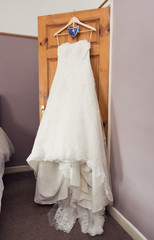 Fototapeta na wymiar A beautiful elegant cream and white Wedding dress hanging on the door in the bride