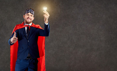 A businessman in a superhero costume with a glowing light bulb in his hand. Concept ideas, success.