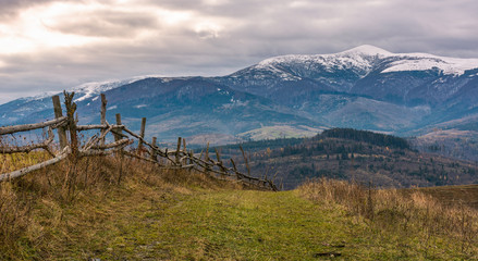 wooden fence on hills of mountainous countryside. agricultural fields in late autumn gloomy...