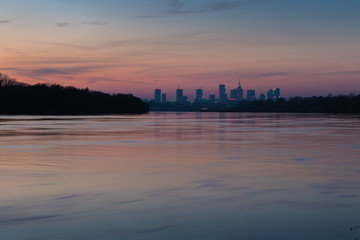 Warsaw skyline with downtown skyscrapers and the Vistula River in red orange light of the setting sun