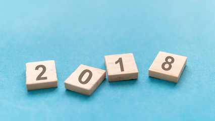 2018 word in wooden block on blue background, blur and select focus